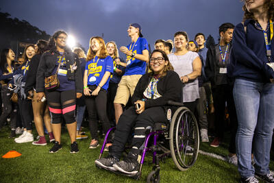 Group of students gathered on stadium field, at night, during Golden Bear Orientation