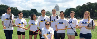 Group of smiling students holding rakes in front of the Capitol Building in Washington, D.S. 