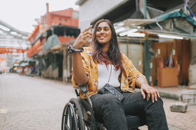 Young woman in wheelchair taking photos in downtown district in Kuala Lumpur