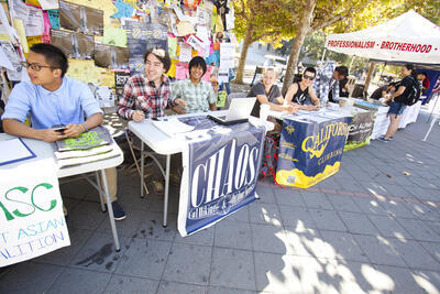 Line of tables with students and signs advertising student organizations